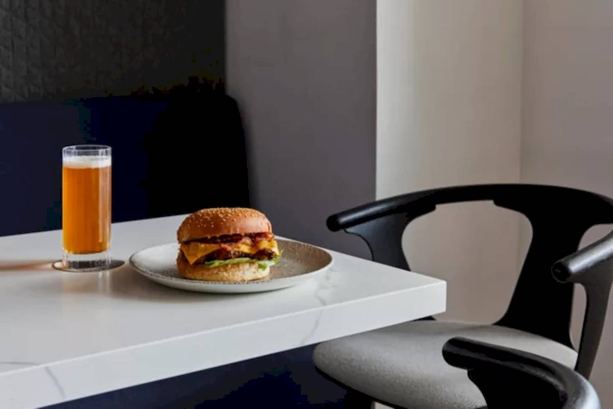Ein Burger und ein Getränk stehen auf einem Tisch in einem Hotel.