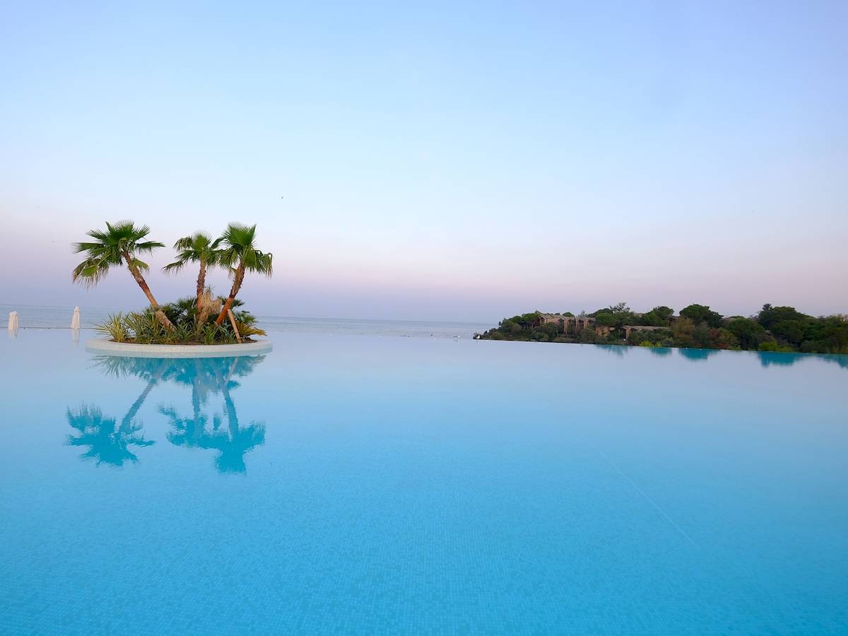 Infinity Pool im Club Marvy mit Palmen und Meer im Hintergrund
