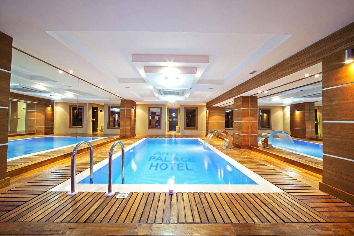 Innenpool des Antea Palace Hotel & Spa mit beleuchteten Wänden und Wasserrutschen.