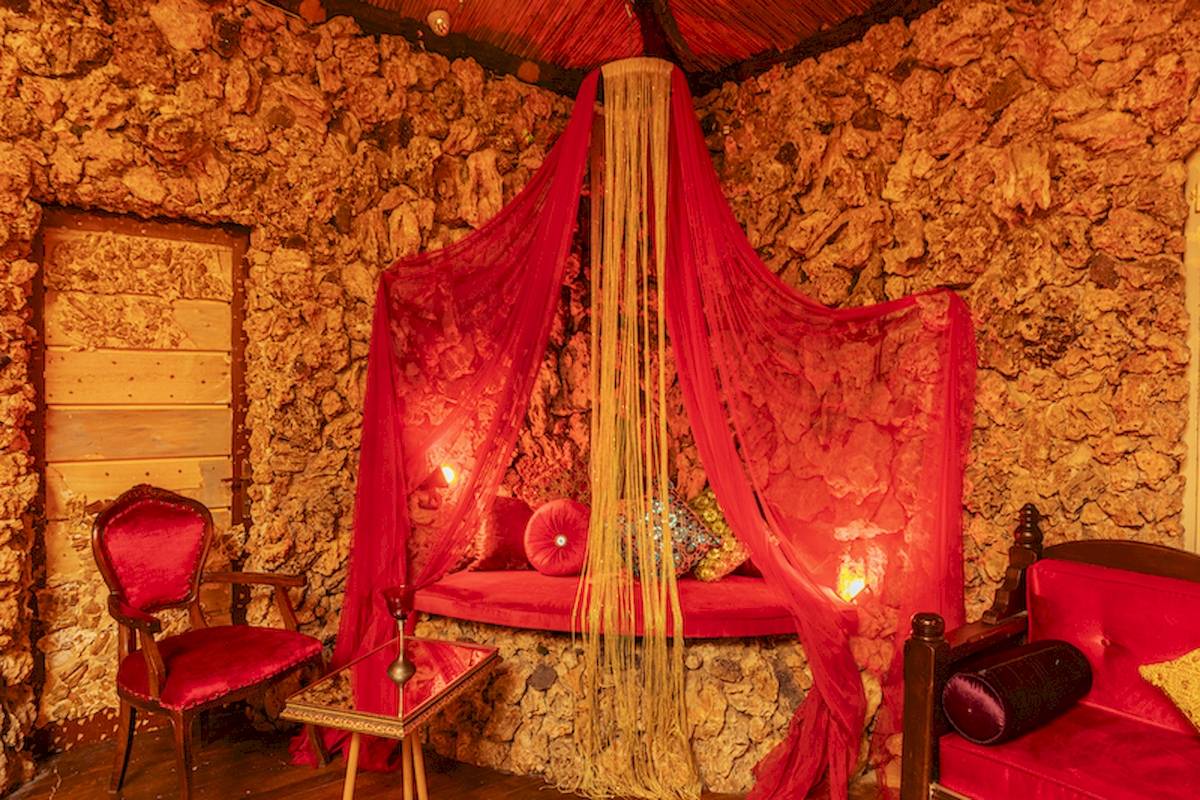 Ein roter Schlafbereich mit Vorhängen und einem Sofa in einer Höhlensuite.