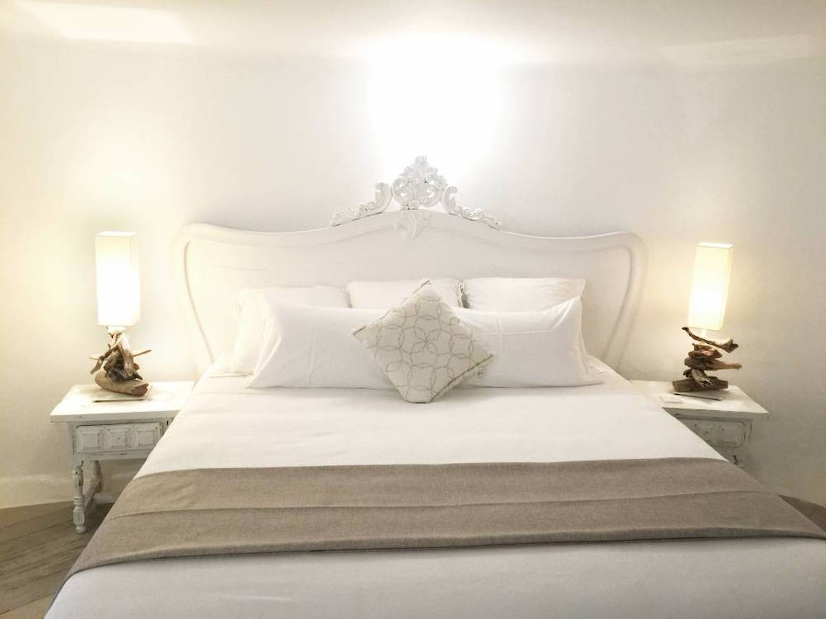 Schlafzimmer im L'Hostellerie du Moulin mit weißem Bett, Kissen und Nachttischen.