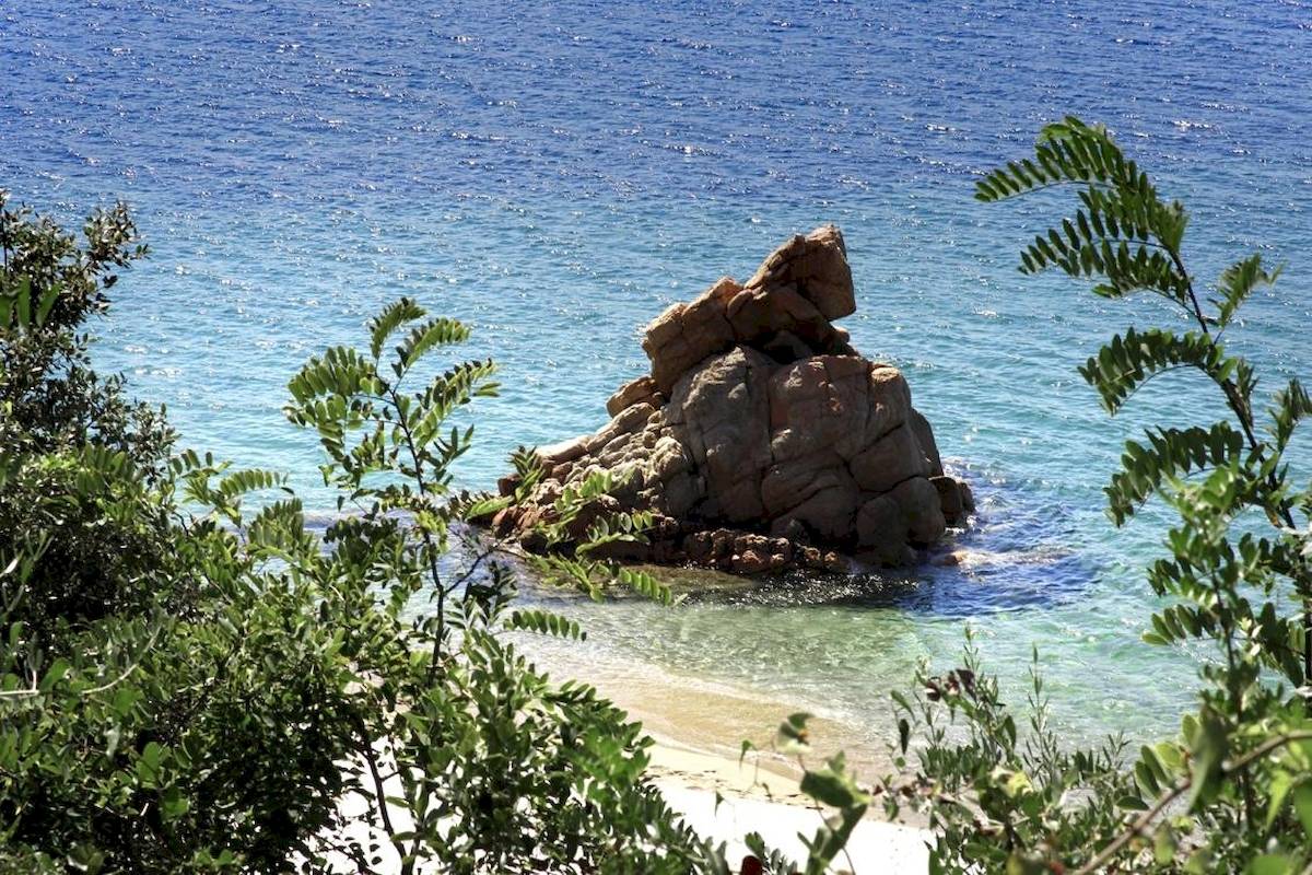 Ein großer Felsbrocken ragt aus dem Wasser am Strand von L'Hostellerie du Moulin.