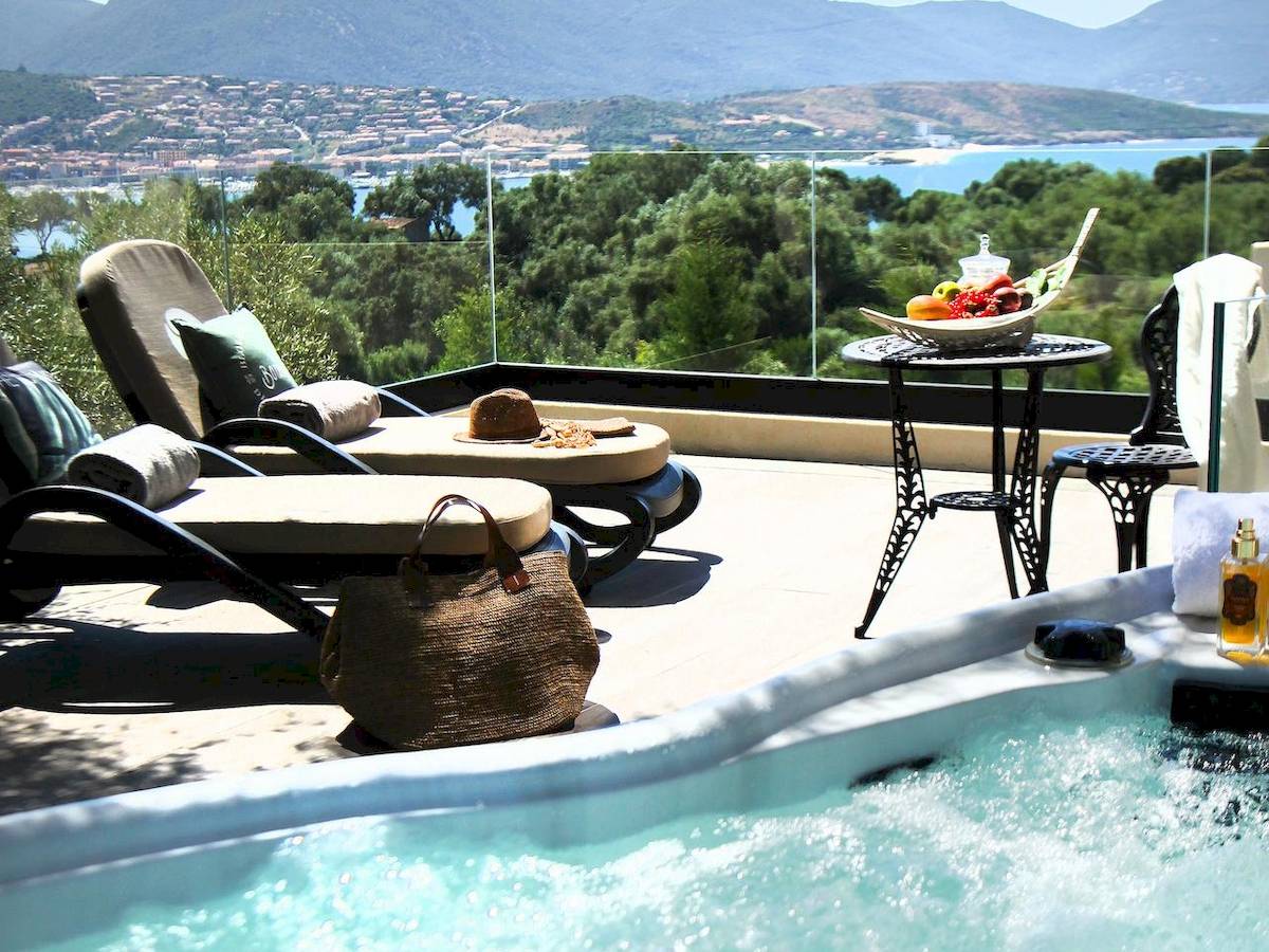 Außenbereich mit Blick auf das Meer, Lounge-Liegesesseln und einem Whirlpool.