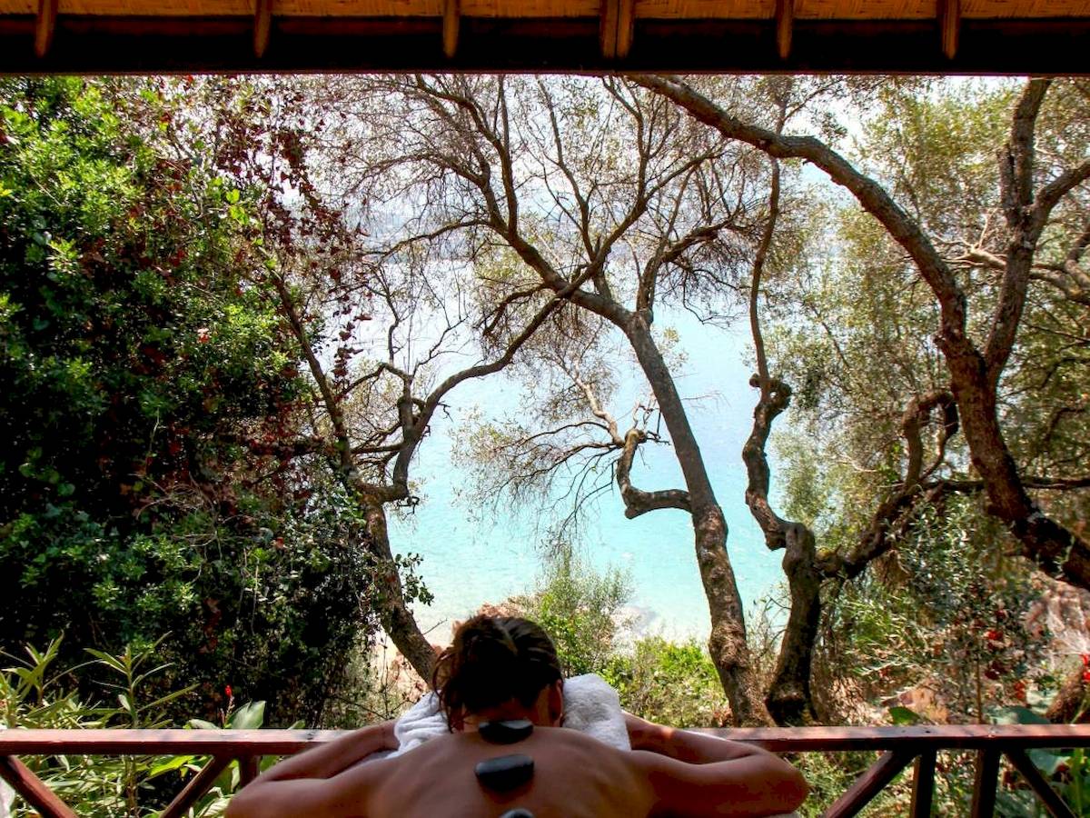 Massage auf Holzterrasse im L'Hostellerie du Moulin mit Blick auf Bäume und Meer