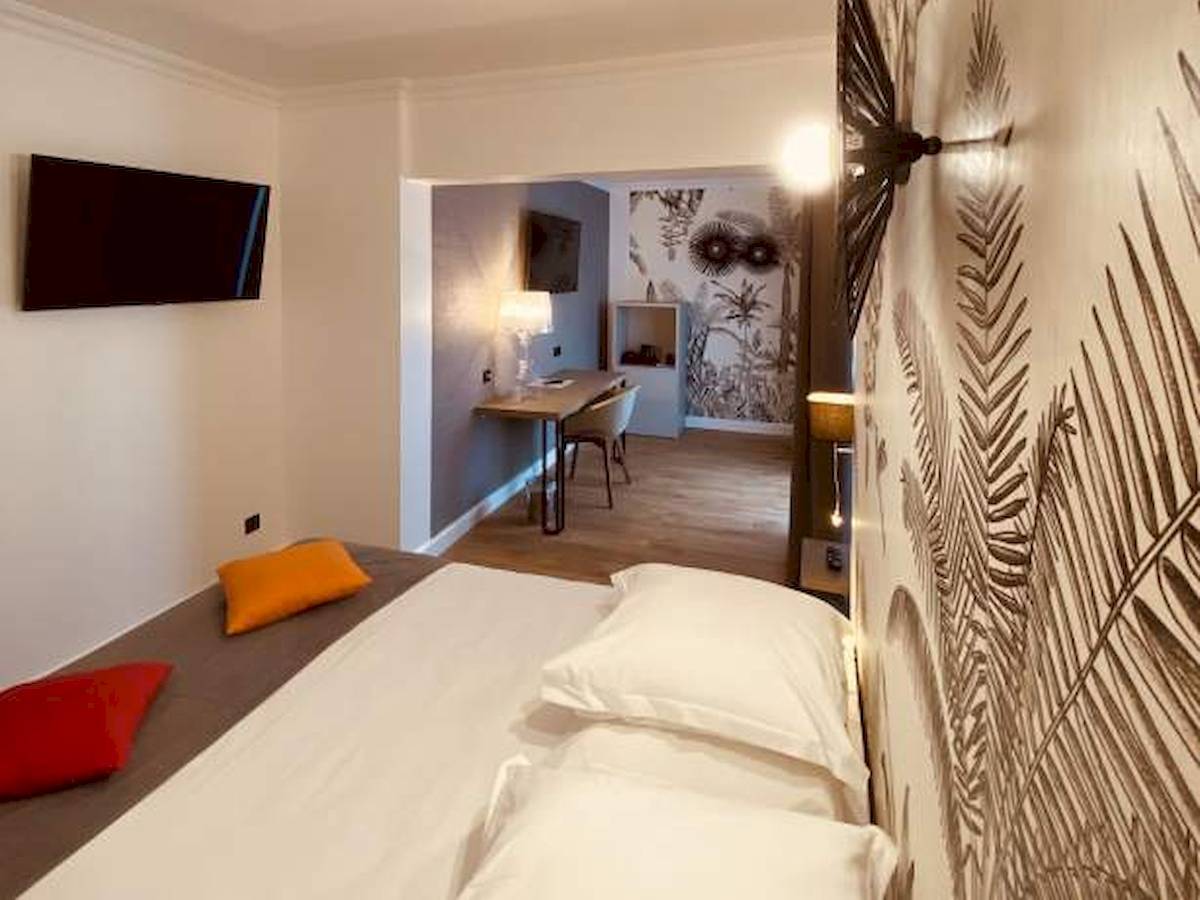 Schlafzimmer im La Lagune Hotel mit Bett, Fernseher und Schreibtisch.