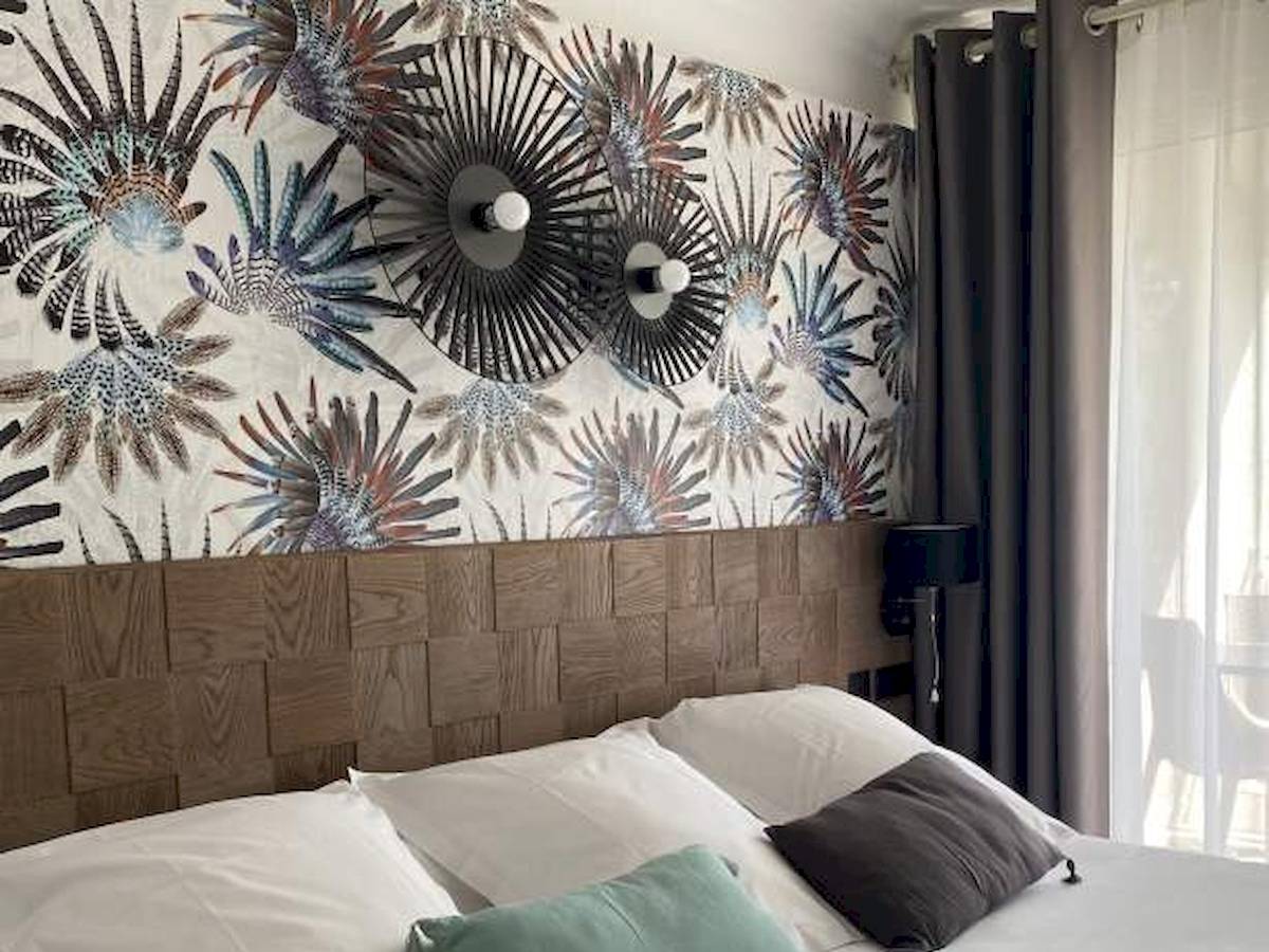 Schlafzimmer im Hotel La Lagune mit bedrucktem Kopfteil und weißen Kissen