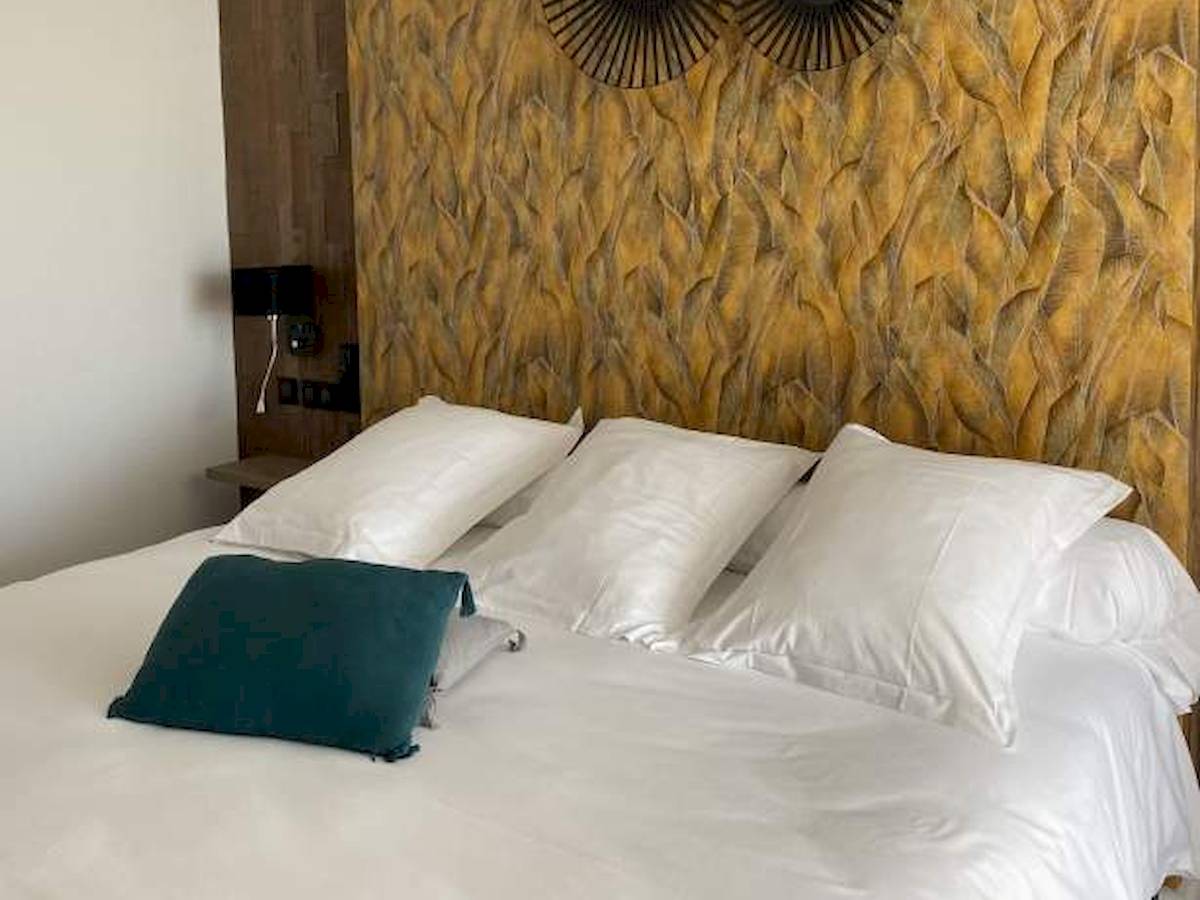 La Lagune Hotelzimmer mit blauem Kissen auf weißem Bett und dekorativer Wand