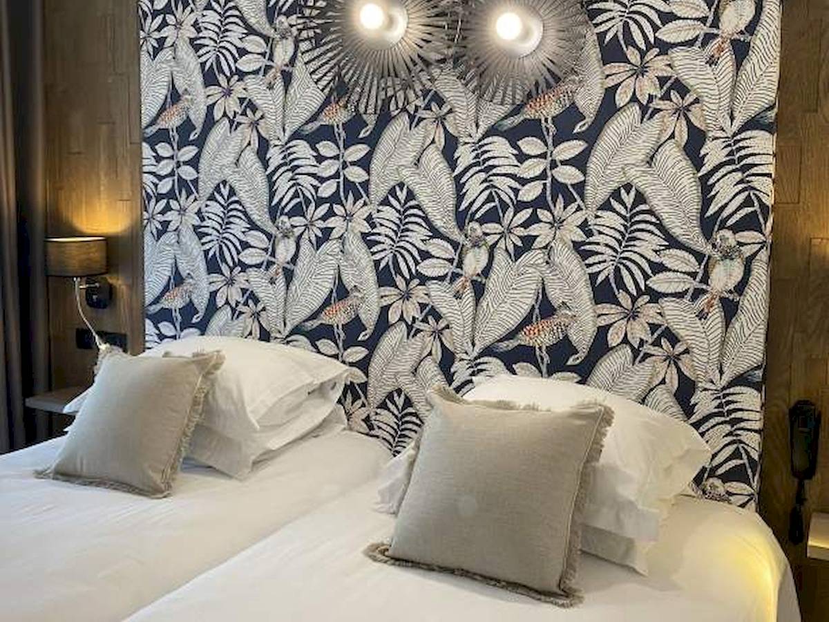 Doppelbett im La Lagune Hotel mit tropischem Wanddesign und Lampen