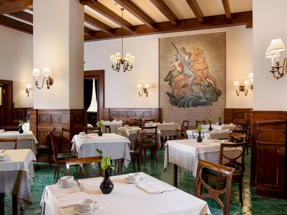 Innenansicht des Restaurants im Bettoja Hotel Mediterraneo mit gedeckten Tischen und Wandgemälde.