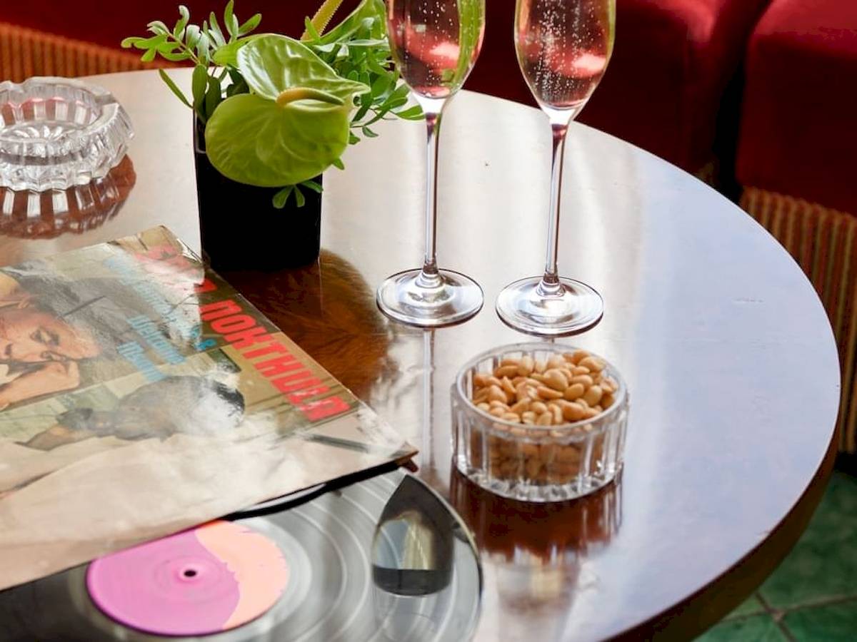 Tisch im Bettoja Hotel Mediterraneo mit zwei Gläsern, einer Nussschale und einer Vinyl-Scheibe.