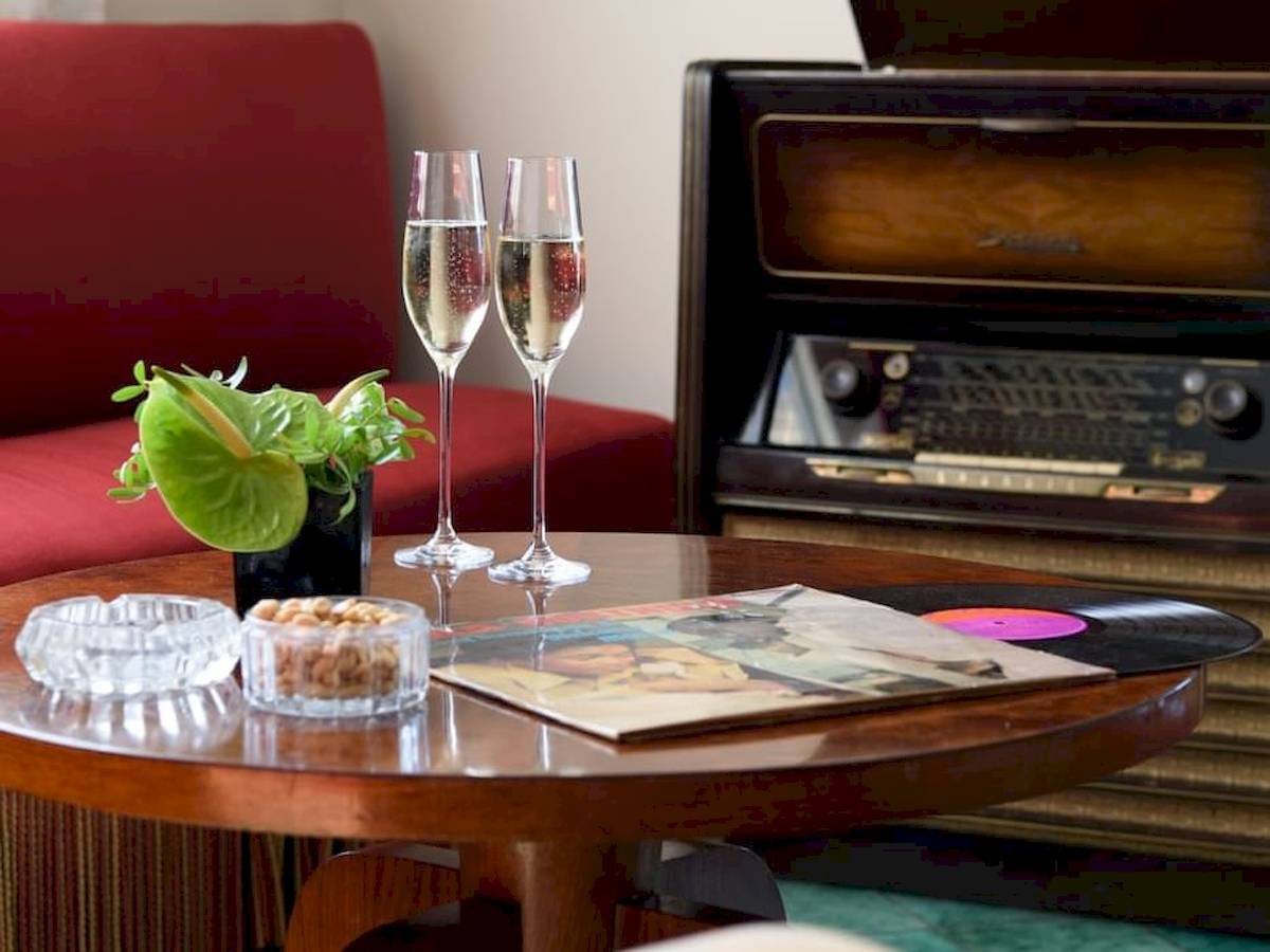 Zwei Cocktails auf einem Tisch im Bettoja Hotel Mediterraneo mit einer alten Schallplatte, einer Pflanze und einer Jukebox im Hintergrund.