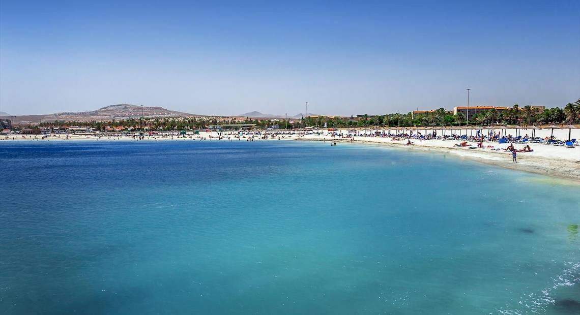 Strand mit vielen Menschen und blauem Wasser vor dem Barcelo Fuerteventura Castillo Hotel.