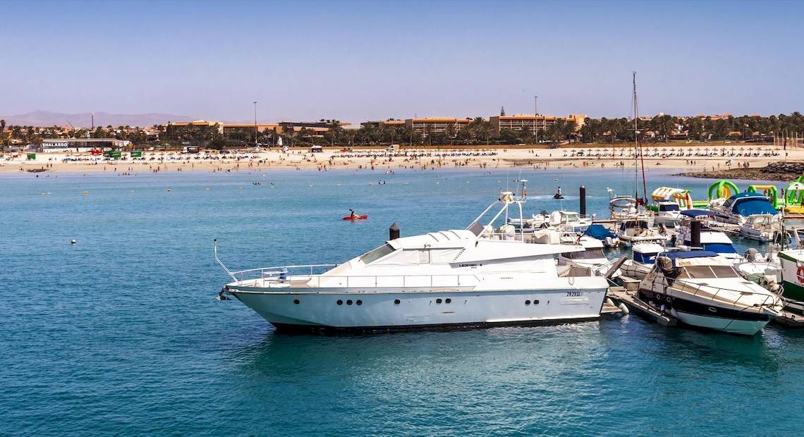 Ein weißes Luxusschiff, das am Hafen neben anderen Booten vor dem Barcelo Fuerteventura Castillo Hotel liegt.