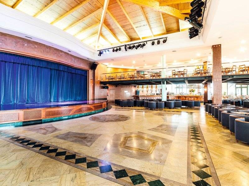 Innenbereich des Punta Prima Resort & Spa mit Bühne, Bestuhlung und Barbereich