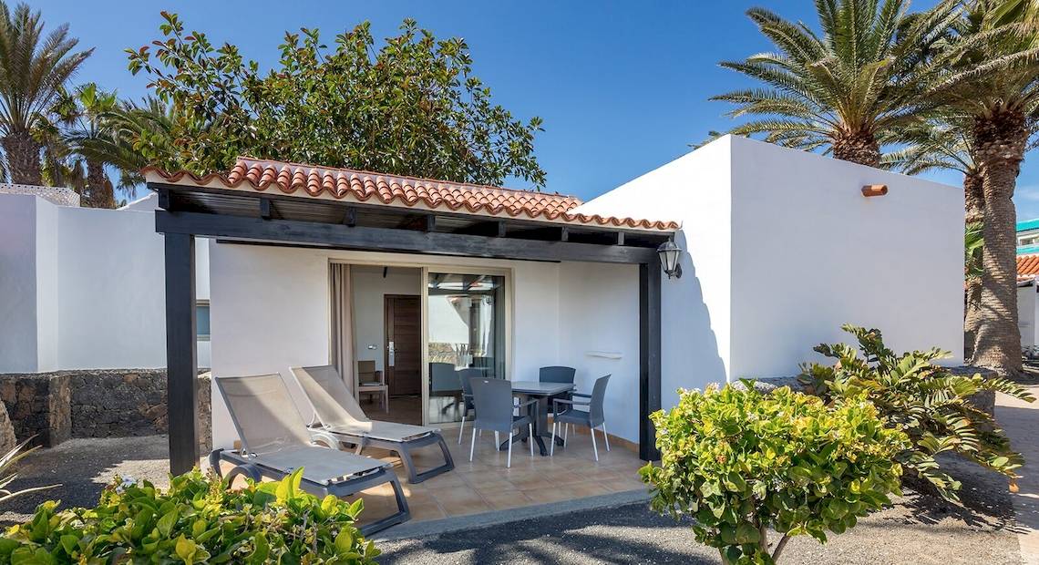 Außenbereich der Barcelo Fuerteventura Castillo Hotel mit Terrasse, Tischen und Stühlen.