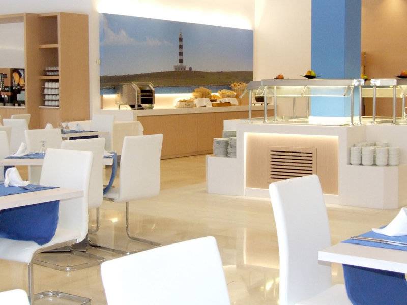Frühstücksraum im Globales Lord Nelson Hotel mit weißen Stühlen und blauen Tischdecken.