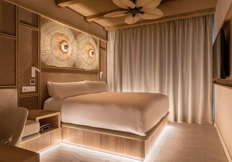 Schlafzimmer im Lago Resort Menorca mit einem Bett, Holzwänden und modernen Leuchten.