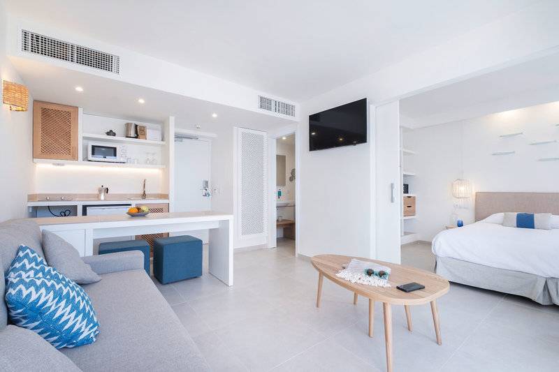 Innenansicht des Carema Beach Menorca Hotels mit Wohnzimmer, Couch, Tisch und Fernseher