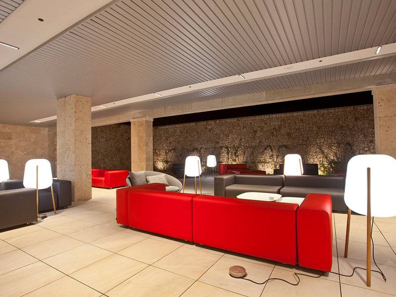Lounge-Bereich im Seth 55 Santo Tomás Hotel mit roten Sofas und weißen Lampen.