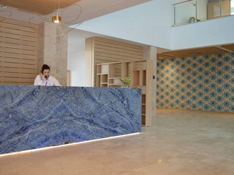 Rezeption des Seth 55 Santo Tomás Hotels mit marmorner Theke und blauem Hintergrund