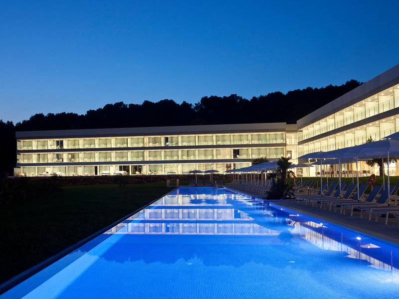 Nachtansicht des Seth 55 Santo Tomás Hotels mit großem Pool und Loungeliegen.