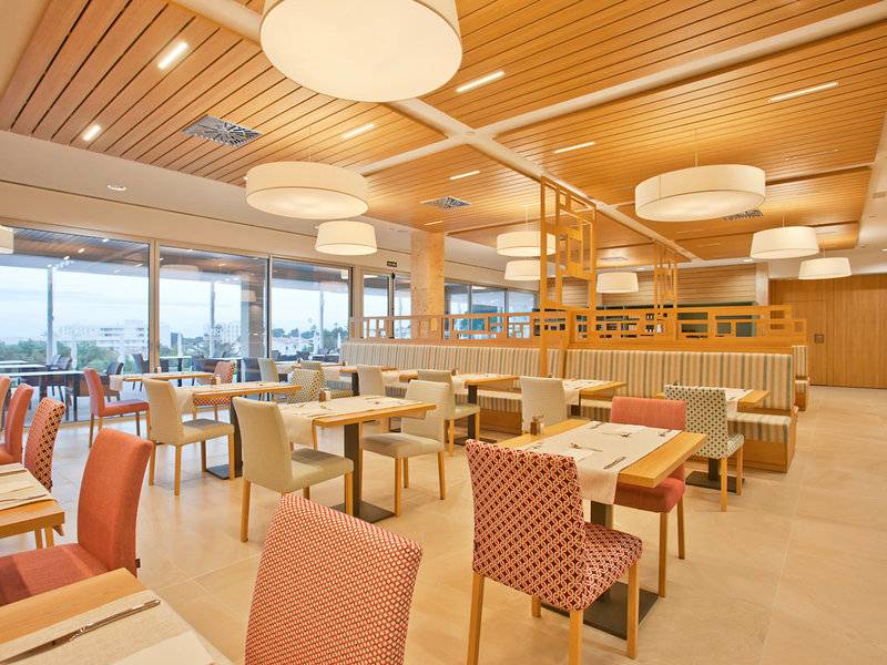 Innenbereich des Seth 55 Santo Tomás Hotels mit Esstischen und Stühlen, Holzdecken und großen Fenstern.