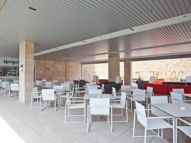Innenlounge des Seth 55 Santo Tomás Hotels mit weißen Tischen und Stühlen und einem roten Sofa.