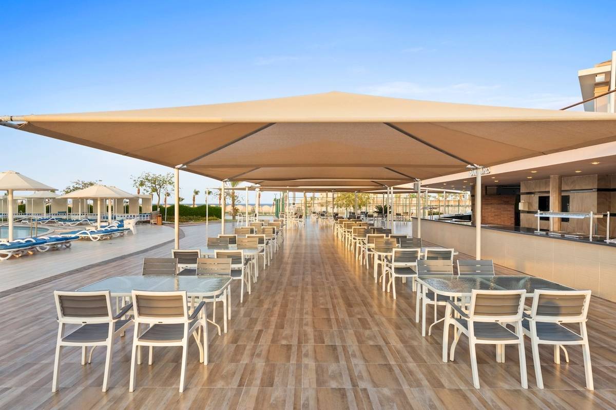 Terrasse des Pickalbatros Aqua Park Resort in Hurghada mit Tischen und Stühlen unter Sonnenschirmen.