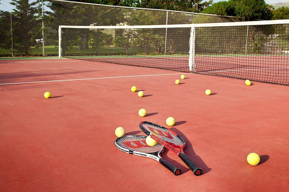 Tennisplatz mit Schlägern und Bällen, alles bereit für ein Spiel.