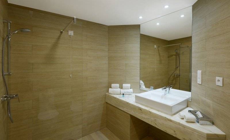 Badezimmer im Baia Azul Hotel mit einer Dusche, Waschbecken und Handtüchern.