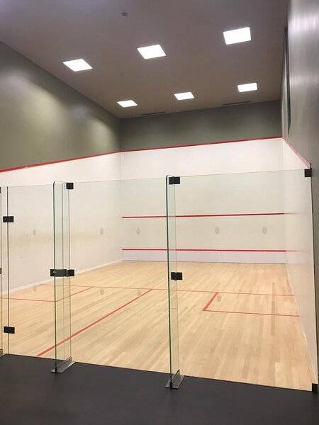 Leerer Squashplatz im Saccharum Hotel mit Glaswänden und hölzernem Boden.