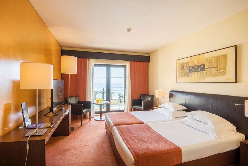 Doppelzimmer im Hotel Vila Galé Santa Cruz mit Meerblick, zwei Betten, Fernseher und Schreibtisch.
