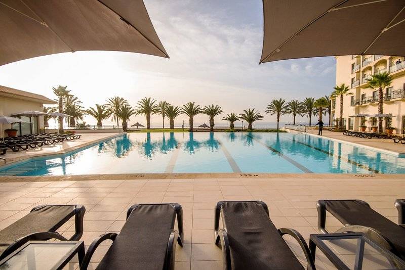 Außenpool des Vila Galé Santa Cruz Hotels mit Liegestühlen und Sonnenschirmen.