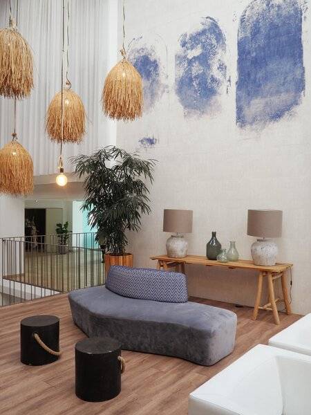 Ansicht der Lobby des Views Oasis Hotels mit moderner Einrichtung, grauer Couch, blauen Wandmalereien und Hängelampen.