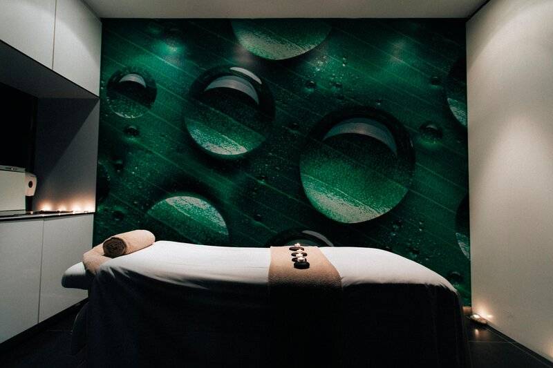 Massageraum im Views Oasis Hotel mit grünem Blattmuster und Wassertropfen auf der Wand.