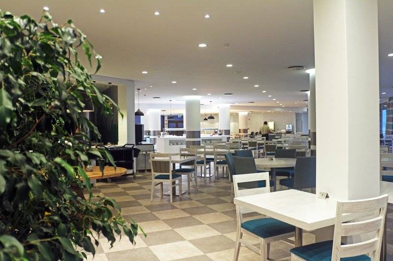 Innenbereich des Restaurants im Views Oasis Hotel mit weißen Tischen und Stühlen, beleuchteten Säulen und gemustertem Boden.