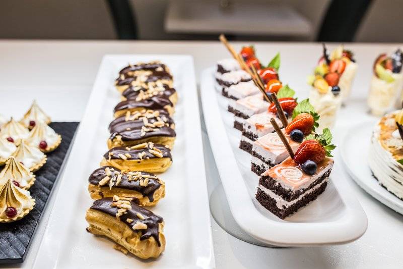 Eine Auswahl an Desserts auf einem Buffet im Views Oasis Hotel, darunter Schokoladencreme-Eclairs, Mini-Kuchen und Meringues.