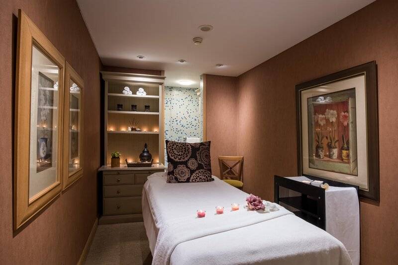 Massageraum im Royal Savoy Hotel mit Liege, Kerzen und Dekor.