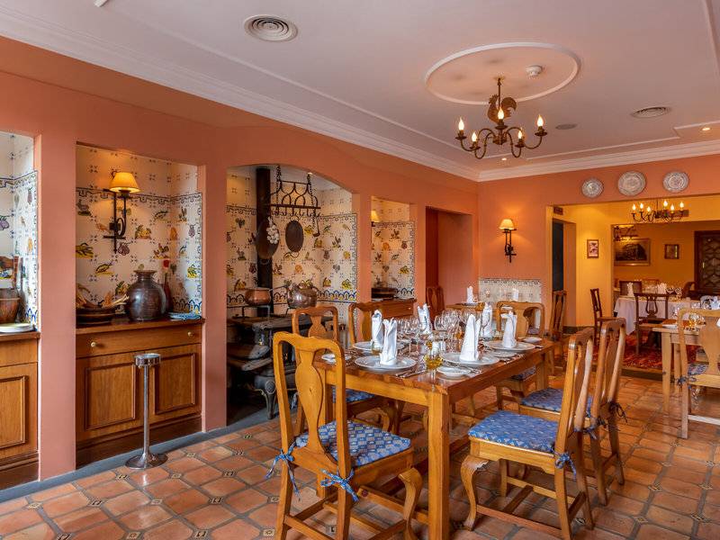 Speisesaal im Pestana Miramar Garden & Ocean Resort mit gedecktem Tisch, Holzmöbeln und traditioneller Wanddekoration.