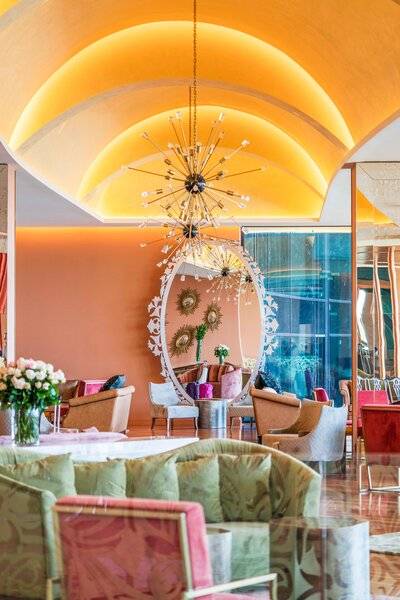 Innenansicht des Savoy Palace Hotels mit Loungebereich, großen Spiegel und gelben Decken.