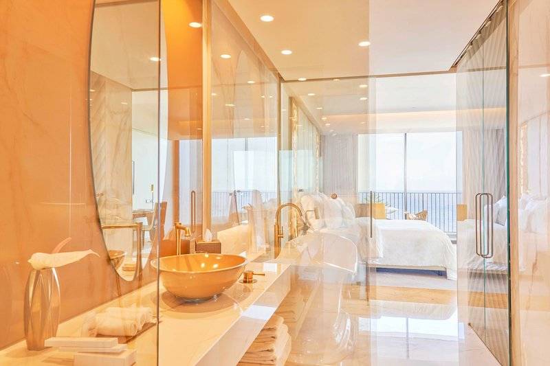 Modernes Badezimmer mit Glaswänden, großem Spiegel und Badewanne im Savoy Palace Hotel.