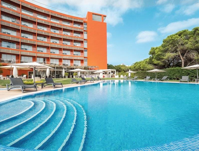 Außenbereich des Aqua Pedra dos Bicos Hotel mit Swimmingpool, Sonnenliegen und Sonnenschirmen.