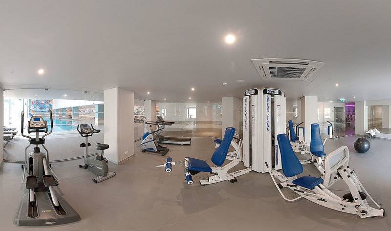 Fitnesscenter im Vila Galé Cerro Alagoa Hotel mit verschiedenen Trainingsgeräten und Blick auf den Pool.