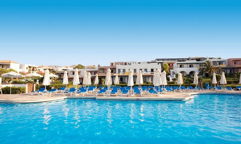 Außenpoolbereich des Mitsis Cretan Village Hotels mit weißen Liegestühlen und Sonnenschirmen
