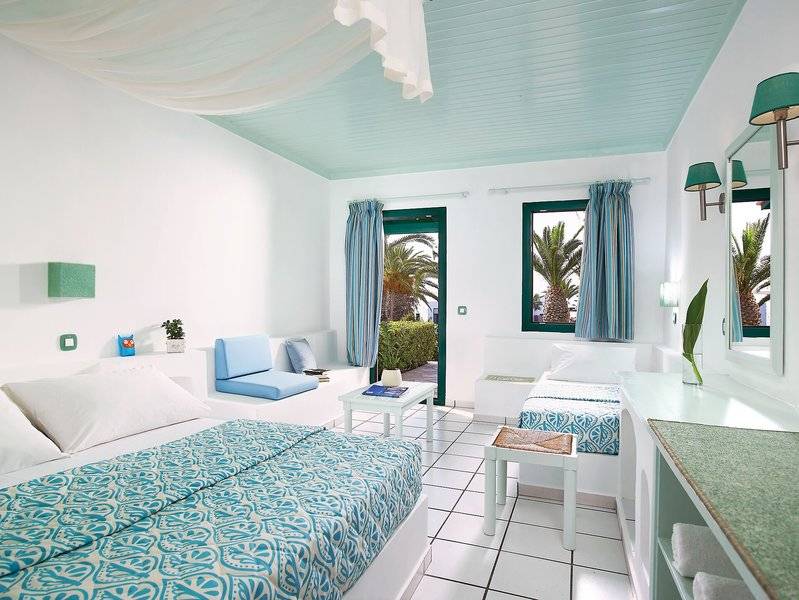 Doppelzimmer im Mitsis Cretan Village Hotel mit zwei Betten, weißem Interieur und blauen Akzenten.