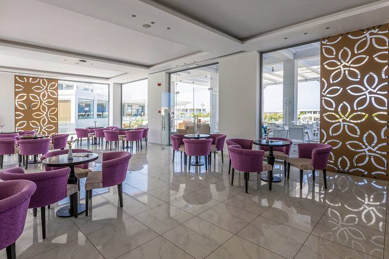 Innenbereich des Asterias Beach Resort mit violetten Stühlen und Tischen.