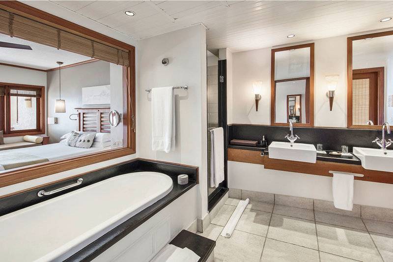 Badezimmer im Heritage Awali Golf & Spa Resort mit Badewanne und Spiegeln.