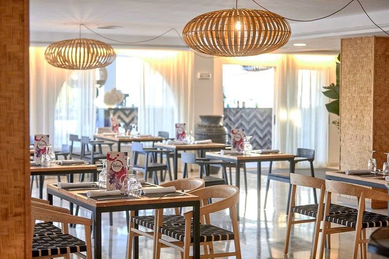 Innenbereich des Fergus Style Bahamas Hotels mit Restauranttischen und hängenden Lampen.