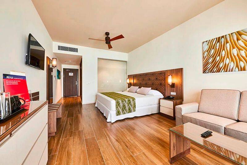 Innenansicht eines Hotelzimmers im RIU Atoll Hotel mit Bett, Couch, Fernseher und Schreibtisch.