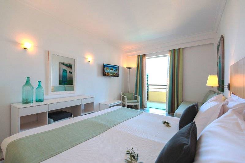 Hotelzimmer im Samaina Inn mit Bett, Fernseher und Balkon.